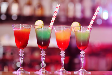 beautiful fresh alcoholic cocktails with mixed colored layers on the background of a bar in a nightclub.