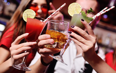 Time Selfie. A group of friends at a party in a nightclub clink glasses with alcoholic beverages. Happy young people with cocktails in the pub.