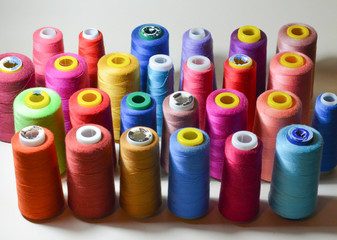 Color sewing threads on white background, top view