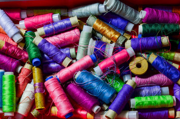 A lot of sewing colored thread on a white table. The view from the top.