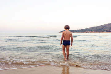 Fototapeta premium Child entering water at sunset