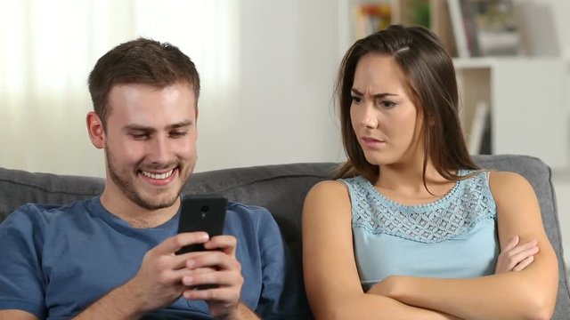 Jealous wife scolding her husband who is using a smart phone at home