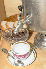 a fragment of a samovar on an old wooden table, bread and a tea