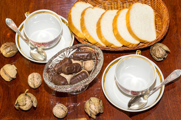 bread, chocolates and two cups on a polished table. top view