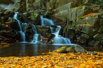 Fototapeta na wymiar Waterfall in autumn forest with long exposure photo