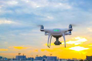 Drone flying on sunset sky in city building
