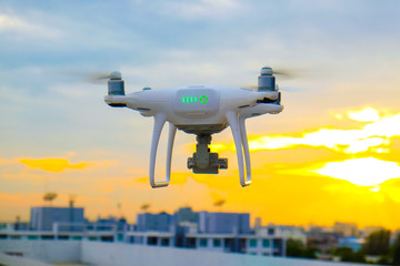 Naklejka na ściany i meble Drone flying on sunset sky in city building