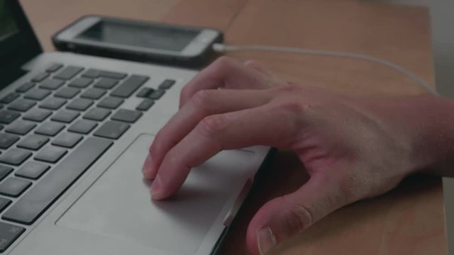 Closeup man's hand scrolls a website using laptop track pad. Business office concept