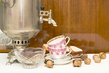 two cups, spoons, walnuts and bread on a polished surface