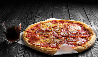 pepperoni pizza on dark black wooden board, traditional italian pizza, glass of cola