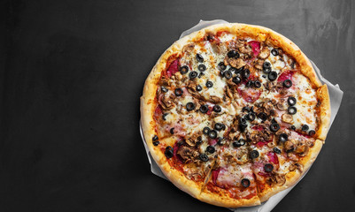 traditional italian pizza on dark black wooden board, top view, place for text