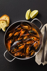 freshly cooked mussels in a frying pan in tomato sauce. pepata di cozze or mussels marinara. classic dish of mediterranean italian cuisine. on black background