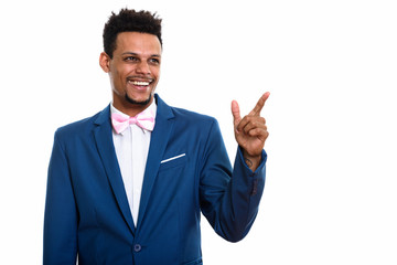 Studio shot of young happy African businessman smiling while thi