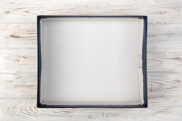 Empty cardboard blue blank box on white wooden background. top view