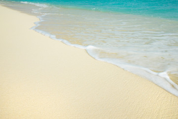 Sea wave on the sunny sandy beach.