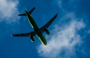 Silhouette of a green plane taking off against a blue sky