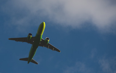 Silhouette of a green plane taking off against a blue sky