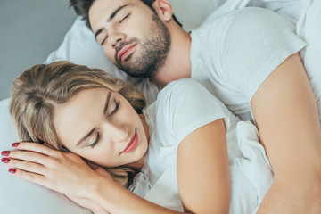 close-up shot of beautiful young couple sleeping together in bed at home