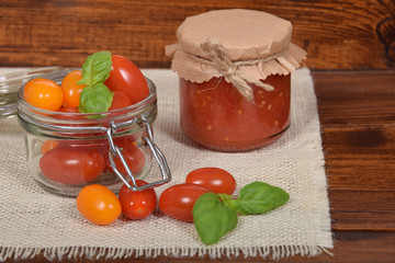 jar with tomato sauce for the winter, cherry tomatoes, garlic, spices, colorful pumpkins and scattered kitchen salt, mortar for the winter