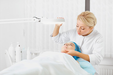 A female dermatologist examines the face of a girl in a cosmetology clinic.