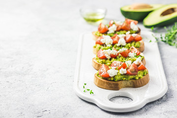 Avocado cherry tomatoes toasts on board. Selective focus, space for text.