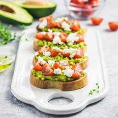 Avocado cherry tomatoes toasts on board. Selective focus, space for text.