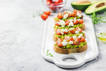 Avocado cherry tomatoes toasts on board. Selective focus, space for text.