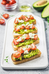 Avocado cherry tomatoes toasts on board. Selective focus, space for text.
