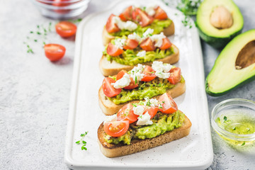 Avocado cherry tomatoes toasts on board. Selective focus, space for text.