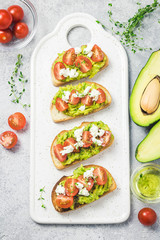 Avocado cherry tomatoes feta cheese toasts on board. Top view, space for text.