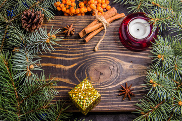 Wooden background with branches of a Christmas tree and a red candle
