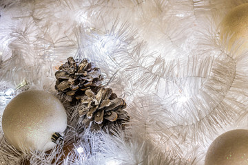 Christmas composition of white jewelry. Tinsel, cones, lanterns and candles. White Christmas snow. Shiny holiday decorations in warm soft light with wax candles. Picture of magic night