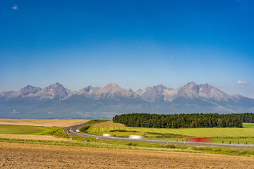 Scenic view of highway leading to rocky peaks of High Tatras mountains, Slovakia summer day.