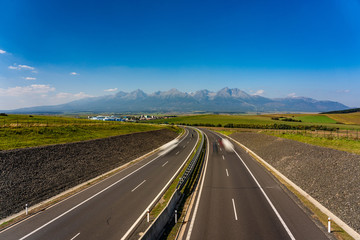 Scenic view of highway leading to rocky peaks of High Tatras mountains, Slovakia summer day.