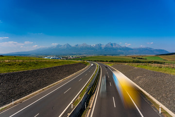 Scenic view of highway leading to rocky peaks of High Tatras mountains, Slovakia summer day.