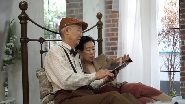 Asian elderly couple using smartphone in vintage home