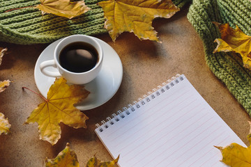 Naklejka na ściany i meble Autumn mood. White cup of coffee, clean sheets notebook and yellow maple leaves, green scarf. 