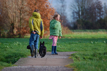 Boy and girl let their dogs out in autumn park.