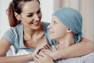 Girl hugging her sick sister with a headscarf