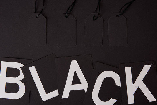 top view of blank price tags and black lettering on black surface, black friday concept