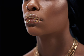 cropped shot of african american woman with sparkling lip gloss isolated on black - obrazy, fototapety, plakaty
