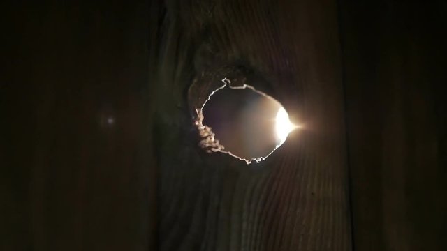 Door hole in the old barn. Someone is spying through a hole in the door.