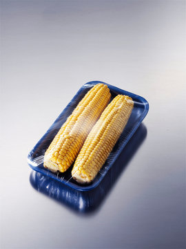 Corn wrapped in plastic on polystyrene tray
