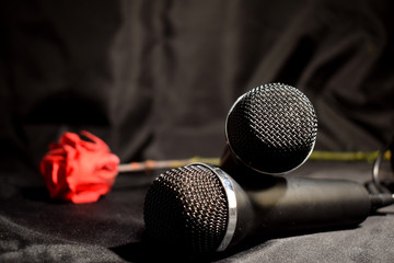 Karaoke set on a black background .. Microphones, a glass of wine and a red rose.