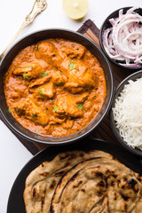 Murgh Makhani / Butter chicken tikka masala served with roti / Paratha and plain rice along with onion salad. selective focus