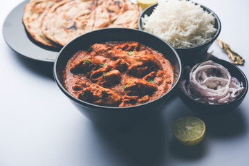 Murgh Makhani / Butter chicken tikka masala served with roti / Paratha and plain rice along with onion salad. selective focus