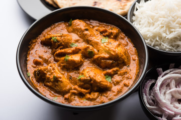Murgh Makhani / Butter chicken tikka masala served with roti / Paratha and plain rice along with onion salad. selective focus