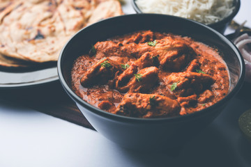 Murgh Makhani / Butter chicken tikka masala served with roti / Paratha and plain rice along with onion salad. selective focus