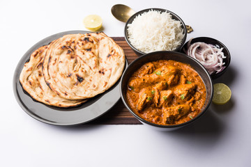 Murgh Makhani / Butter chicken tikka masala served with roti / Paratha and plain rice along with onion salad. selective focus