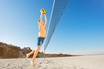 Boy serving the ball during beach volleyball game